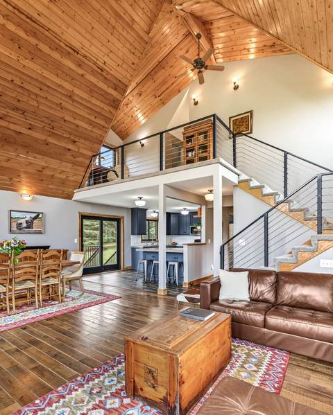 Vaulted living room with stone fireplace and loft overlook